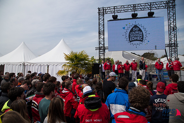 (International students in front of a stage with the huge banner of the EDHEC sailing regatta in the background.