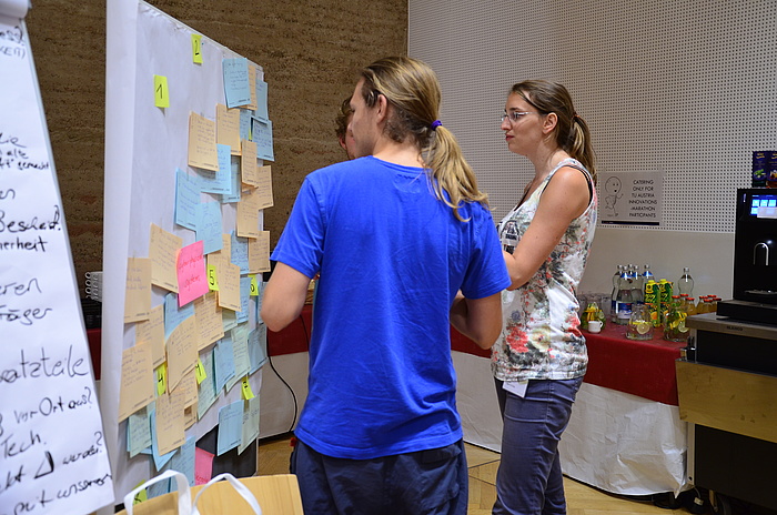 TU Graz-Student Philipp Rouschal (ganz links) mit einer Teamkollegin und einem Teamkollegen vor einer Pinwand voller Ideen beim TU Austria Innovations-Marathon.