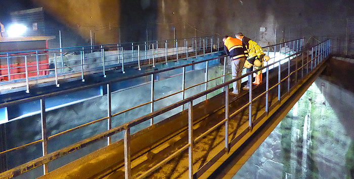 Two workers looking into the huge riser shaft.