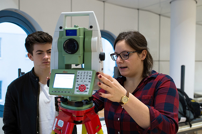 A staff member explains a measuring device to a visitor at the Geoday.