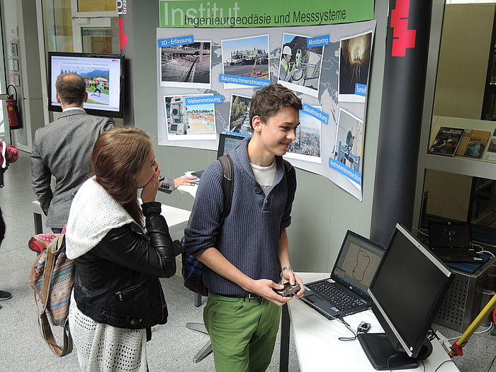 Junge Frau und junger Mann amüsieren sich vor einem Laptop mit einer grafischen Darstellung am geoday2015@TU Graz.