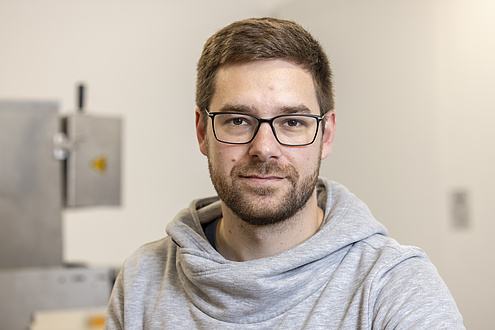 A man with a beard and glasses is looking into the camera.