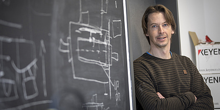 A man leans against a blackboard