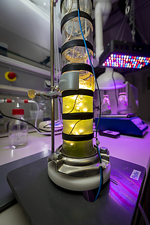 Eine von innen beleuchtete Glasröhre steht auf einem Labortisch.