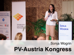 Sonja Wogrin steht auf der Bühne und hält eine Präsentation beim PV-Austria Kongress. Im Hintergrund ist ein Banner der Technologieplattform Photovoltaik zu sehen.