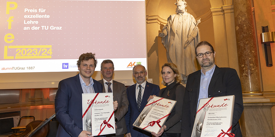 Five people smile into the camera, three of them hold a certificate showing them as winners.