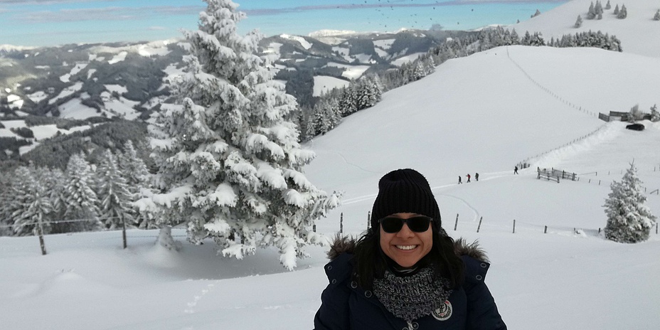 Young woman in winter clothes in snow-covered mountain landscape.