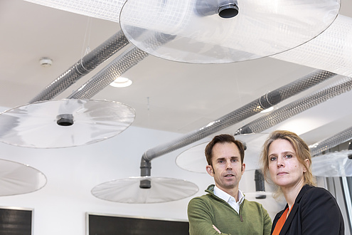 A man and a woman, in the background transparent plate-like objects can be seen on the ceiling.