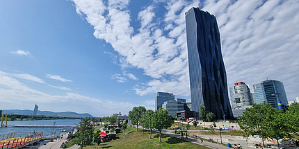 Bild eines hohen, schwarzen Bürogebäudes neben einem Fluss
