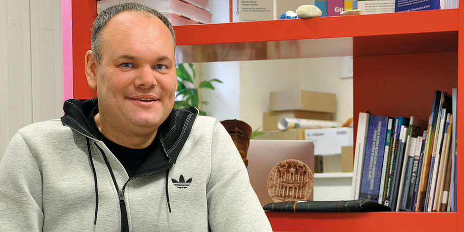 Martin Ebner, Leiter des Bereiches Lehr- und Lerntechnologien an der TU Graz vor einem roten Bücherregal in seinem kunterbunten Kreativ-Büro.
