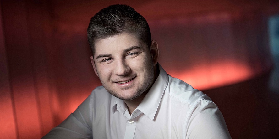 Young man with white shirt in front of red illuminated background