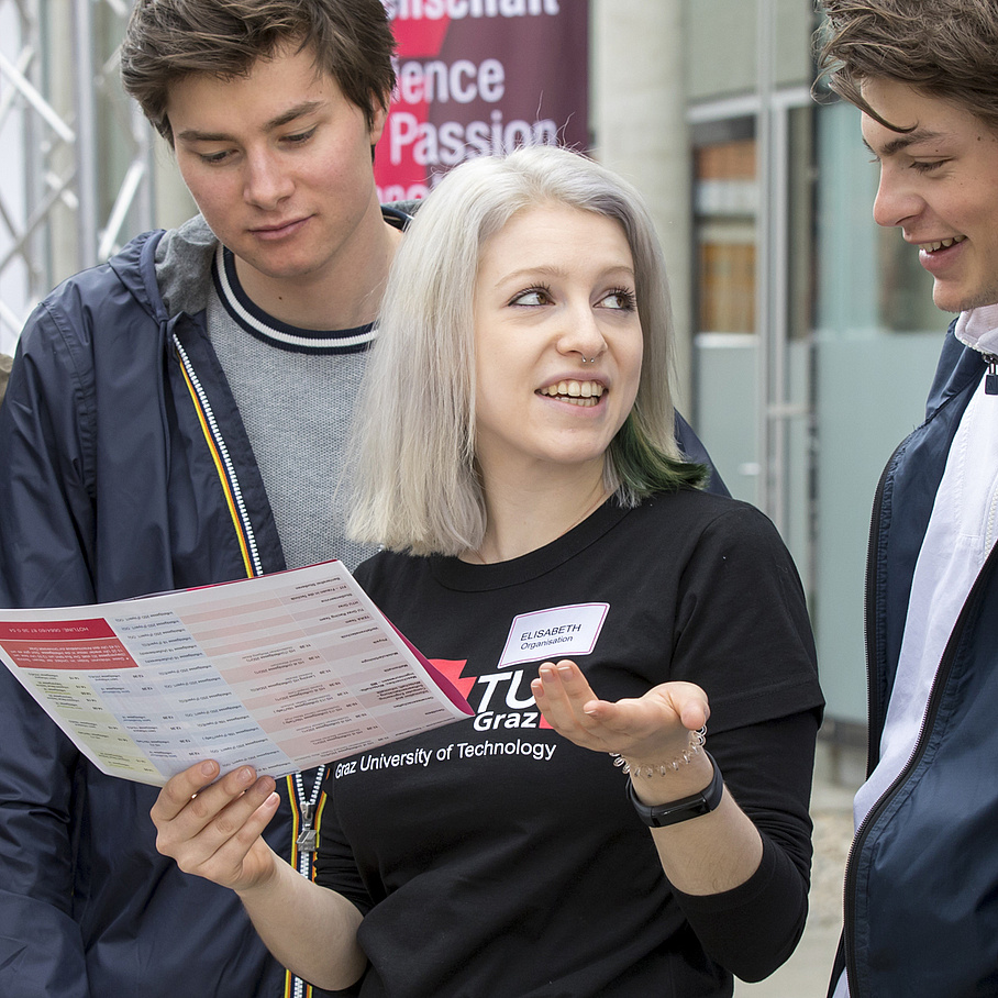 Eine Studentin im Gespräch mit zwei Schülern.
