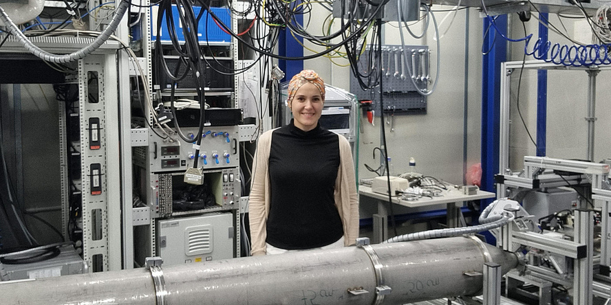 Young woman in front of a small angle x-ray scattering (SAXS) beamline in a major research facility.