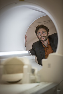 Ein Mann schaut durch eine MRT-Untersuchungsröhre in die Kamera