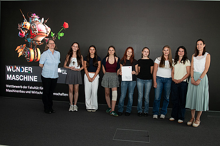 Nine people stand next to each other on a stage and smile into the camera.