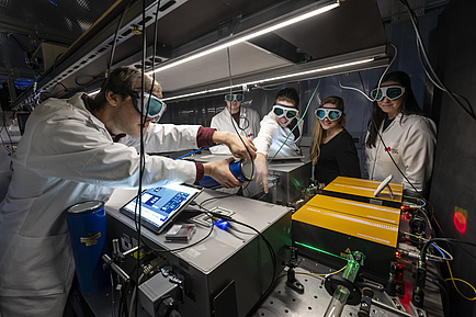 Five people in a laboratory standing around a machine.