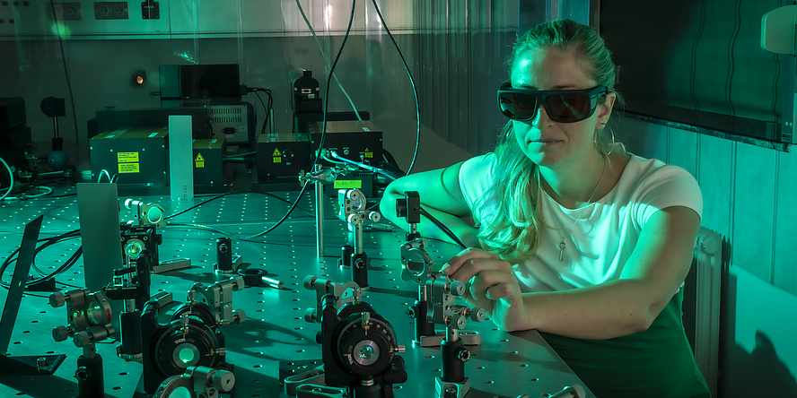 A woman at a laboratory device bathed in green light