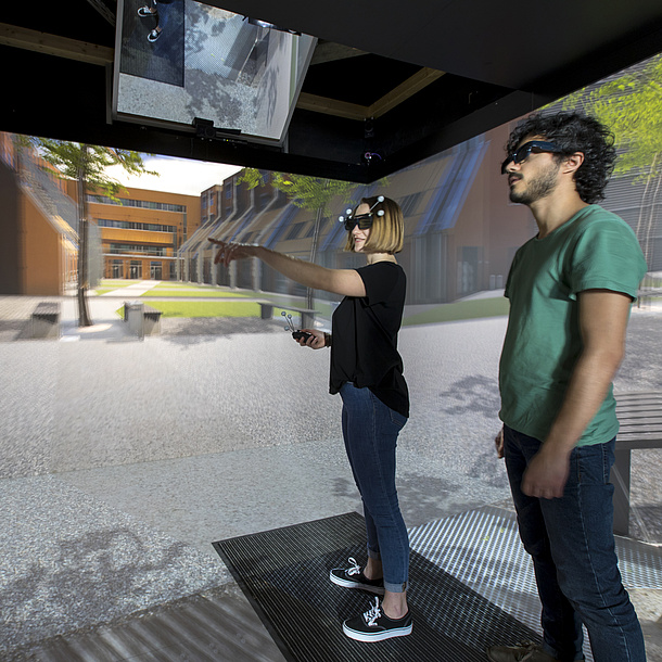Zwei Studierende mit 3D Brillen stehen in einem virtuellen Raum.