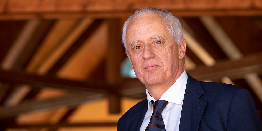 Portrait of a man with black suit and tie, in the background wooden roof truss and trams