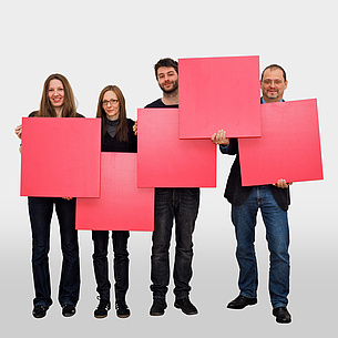 2 Frauen und 2 Männer halten 5 rote Quadrate in Form des TU Graz Logos.