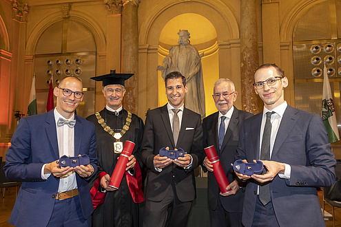 Five smiling men with rings of honour and promotional roles. 