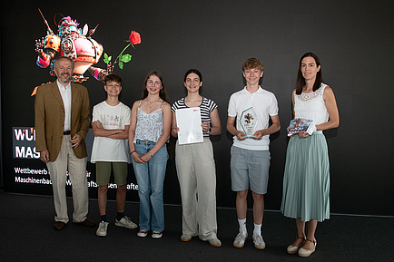 Six people stand on a stage and smile into the camera.