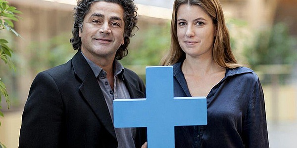 Two people behind a blue cross