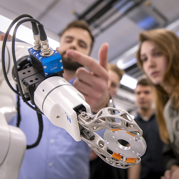 Students in front of a robot gripper arm