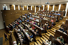 Viele Menschen in einem holzvertäfelten Hörsaal.