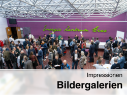 Große Menschenmenge bei einer Kaffeepause im „Energie Zentrum Graz“ vor lila Wand mit Schriftzug, Stehtischen, Buffet und geöffnetem Hörsaal.