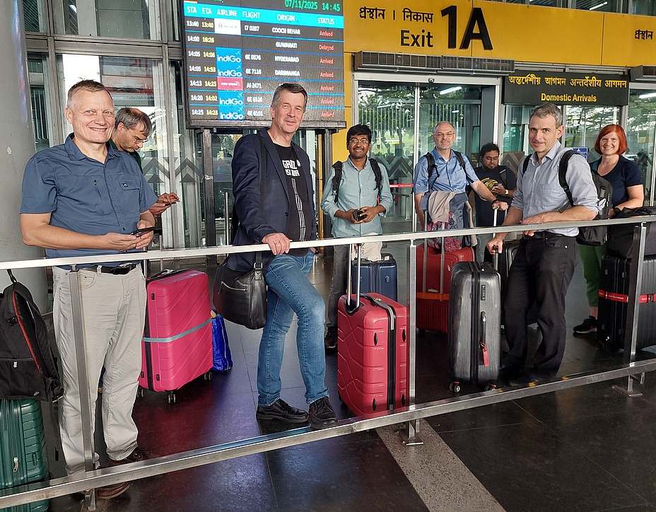 8 Personen warten am Flughafen mit ihren Koffern auf das Einchecken. 