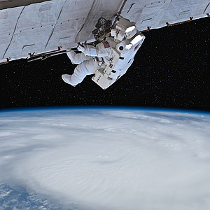 Dieses Bild zeigt einen amerikanischen Astronauten während eines Außeneinsatzes im Weltall. Der Astronaut trägt dabei einen weißen Weltraumanzug, welcher zusätzlich mit einigen Werkzeugen und Überlebenssystemen ausgestattet ist. Der Astronaut ist mi