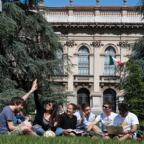 Studierende sitzen auf der Wiese vor einem Gebäude des Politecnico di Milano. Bildquelle: Politecnico di Milano