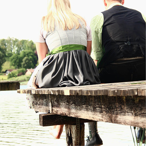 Ein Mann und eine Frau in Tracht sitzen auf einem Steg. Bildquelle: WoGi – Fotolia.com