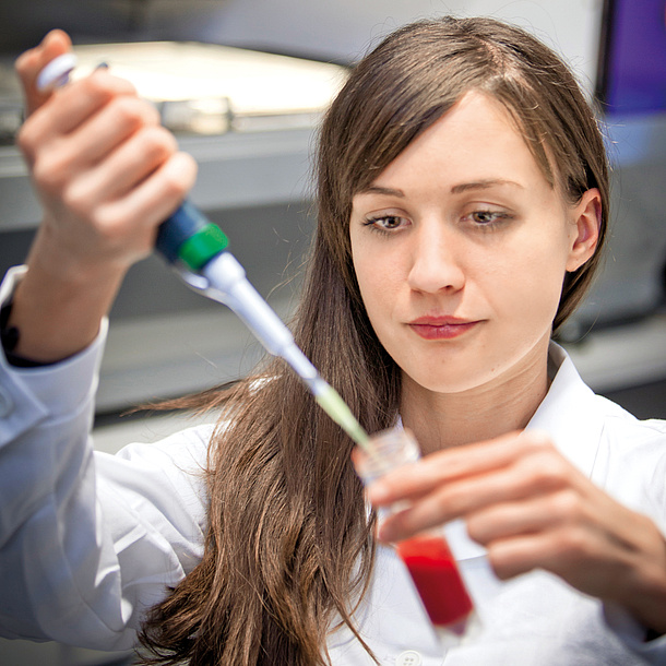 Junge Frau in einem Labor mit einer Pipette.