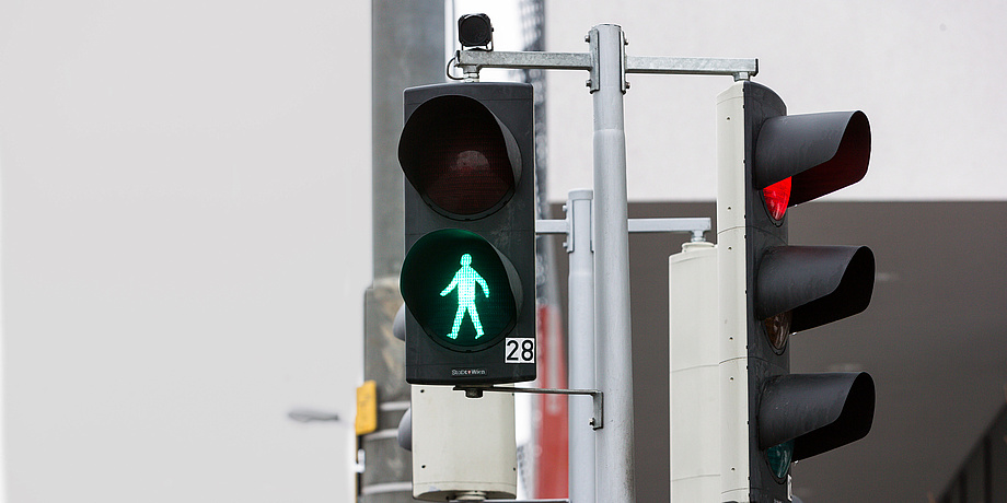 Straßensituation mit Fußgängerampel, die auf grün ist. 