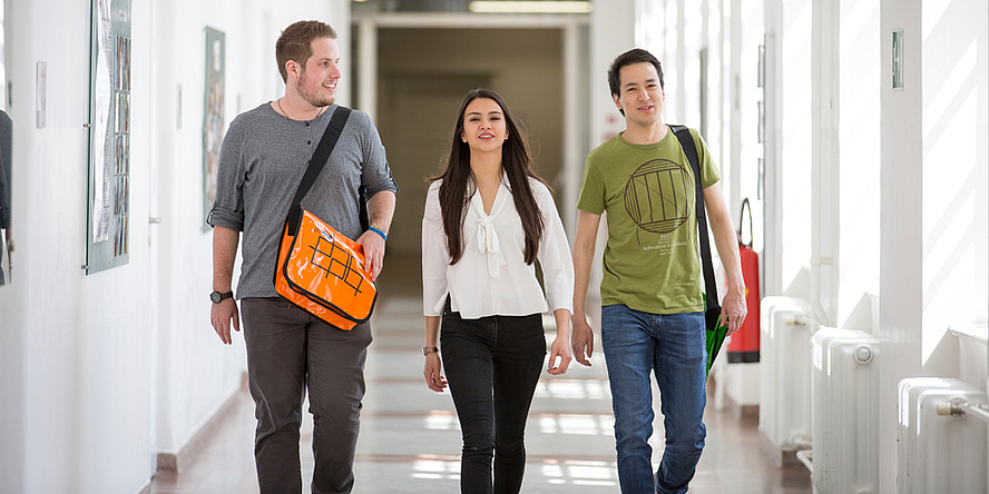 3 students walking along in a goog mood in a building of Graz University of Technology.