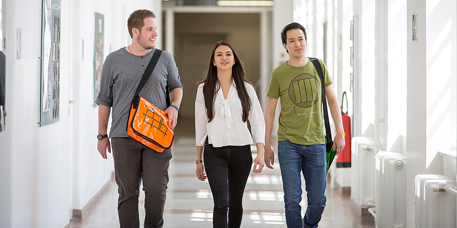 3 students walking along in a goog mood in a building of Graz University of Technology.