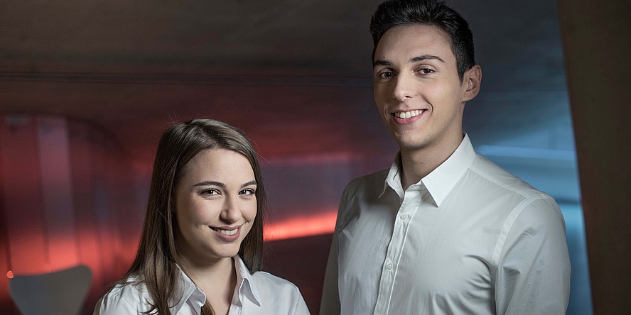 Portrait of a young woman and a young man against a red-blue illuminated background