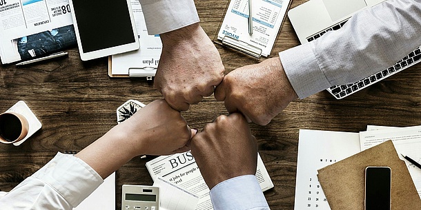 4 hands stretched together over a table