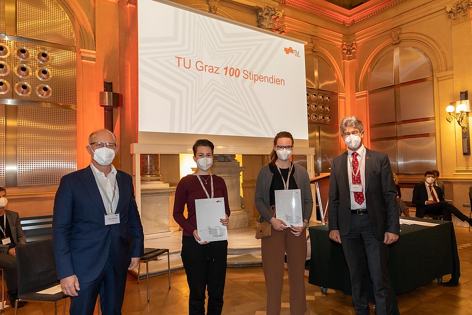 Two female students with certificates, flanked by two men from TU Graz
