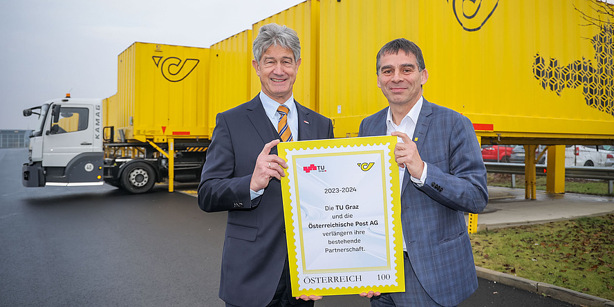 Two men hold a sign into the camera which informs about the extended partnership between TU Graz and Österreichische Post AG