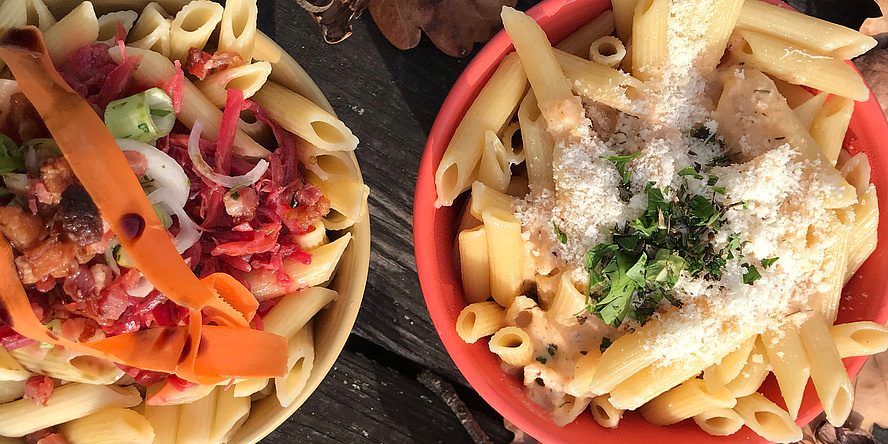 A yellow and a red bowl with colourful noodle dishes photographed from above.