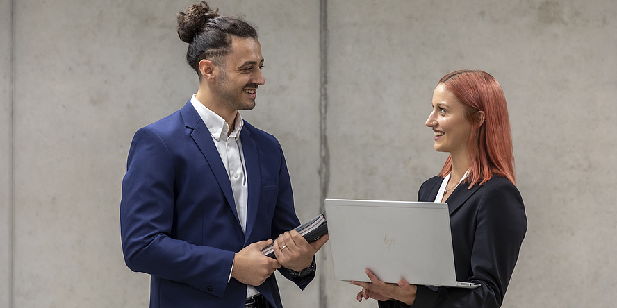 Young man and young woman with laptop and work documents facing each other