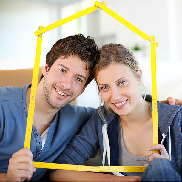 Eine Mann und eine Frau halten einen Zollstab, der die Konturen eines Haus nachbildet. Bildquelle: goodluz – Fotolia.com