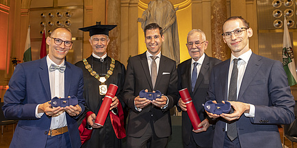 Five smiling men with rings of honour and promotional roles. 