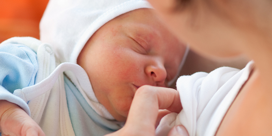 Baby lies in its mothers arms.