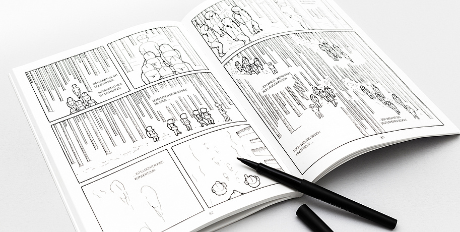 The comic "In Mind" is presented on a white table. The drawings are black and white und are showing people wearing hoodies walking through a forest. There is a black pen next to the comicbook.