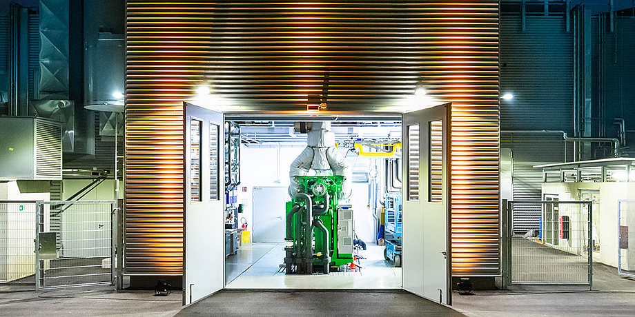 Photo from the outside looking into a hall containing a test stand for large engines.
