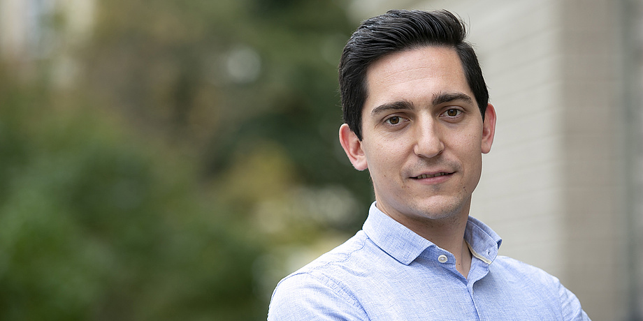 Portrait of a man with short black hair in a blue shirt.